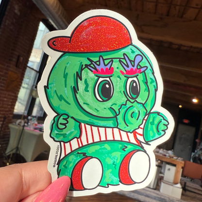 Hand holding a sticker of the philly phanatic.